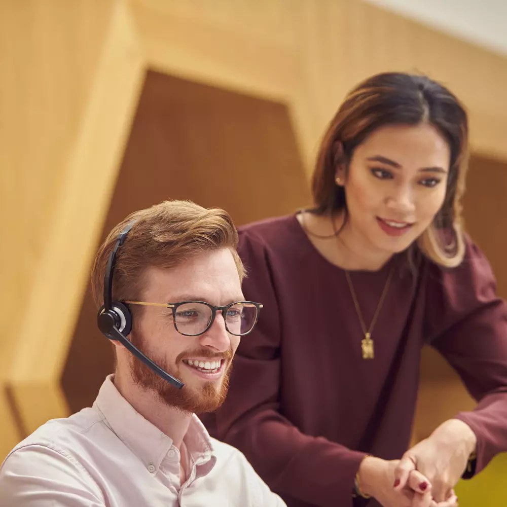Lees meer Twee klantenservice collega's kijken naar een beeldscherm buiten beeld.